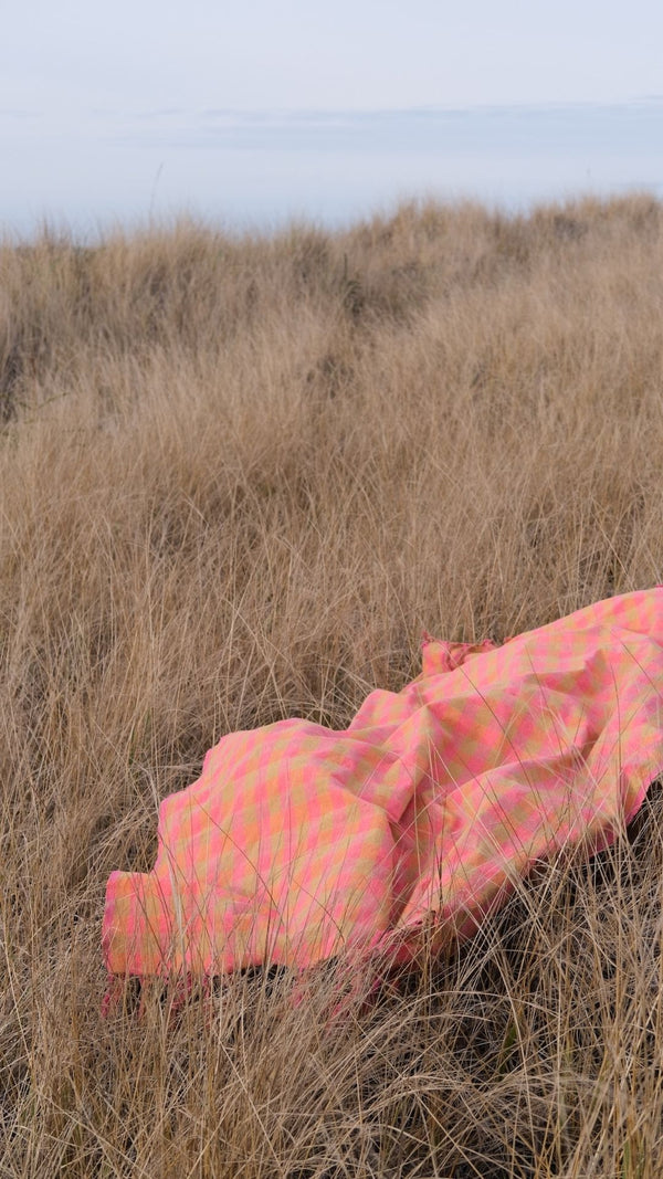 pink and yellow picnic blanket in wheat field or beach towel