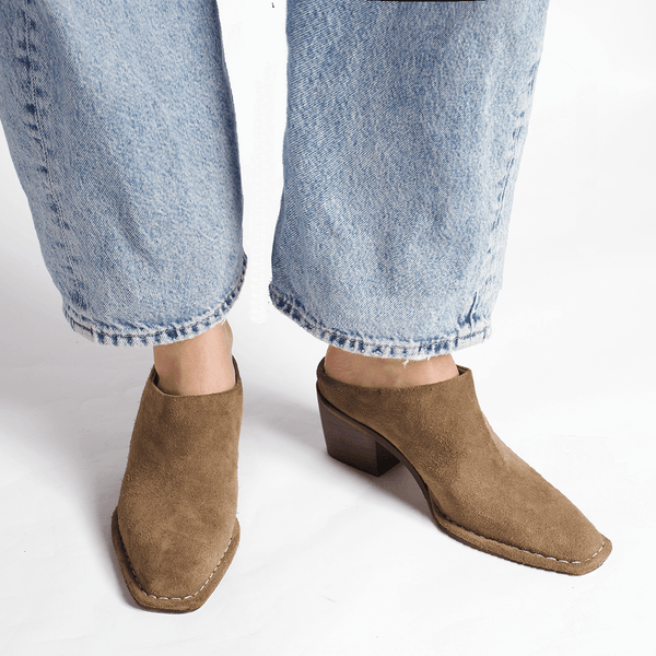 Brown ankle boots worn with light blue jeans on a white background