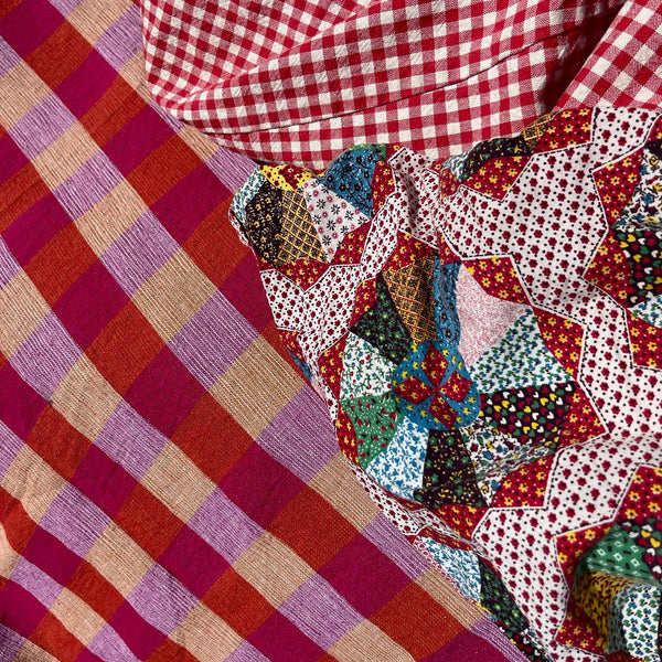 Close-up of checkered and patchwork fabric. Plaid towel with tassels on a textured surface. Checker Gingham Picnic Blanket.