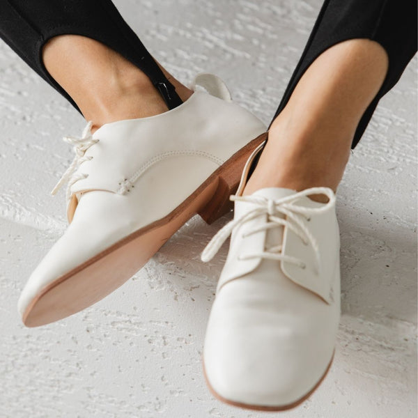 white leather oxford lace up derby glove flat ballerina close up on foot